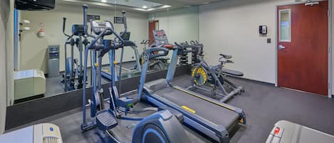 A gym with various exercise equipment including treadmills, elliptical machines, and stationary bikes.