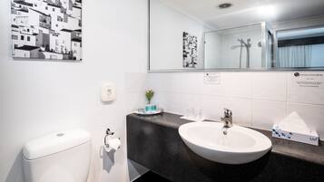 Un baño con lavamanos blanco, inodoro, espejo y encimera negra.