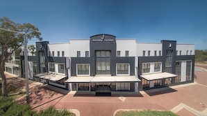 Um hotel moderno com entrada central, várias varandas e telhado plano.