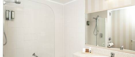 Un baño moderno con ducha de vidrio, bañera independiente y tocador con lavamanos y espejo.