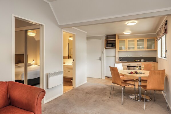 Un appartement moderne comprenant un coin repas, une cuisine et une chambre avec un lit et une table de chevet.