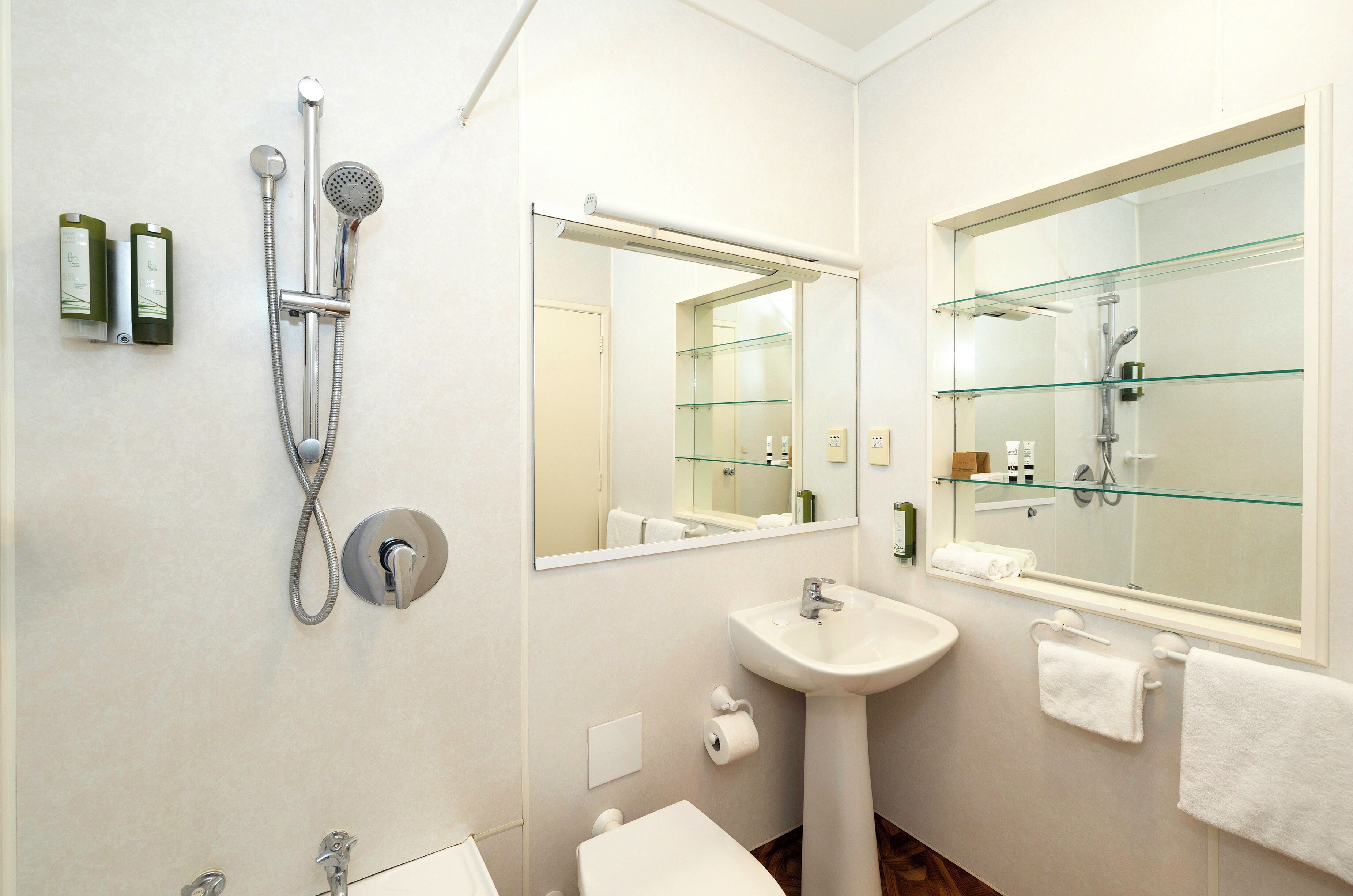 Un baño moderno con cabina de ducha de vidrio, un lavabo y un espejo grande.