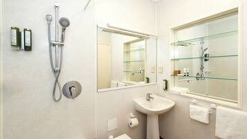 Un baño moderno con cabina de ducha de vidrio, un lavabo y un espejo grande.