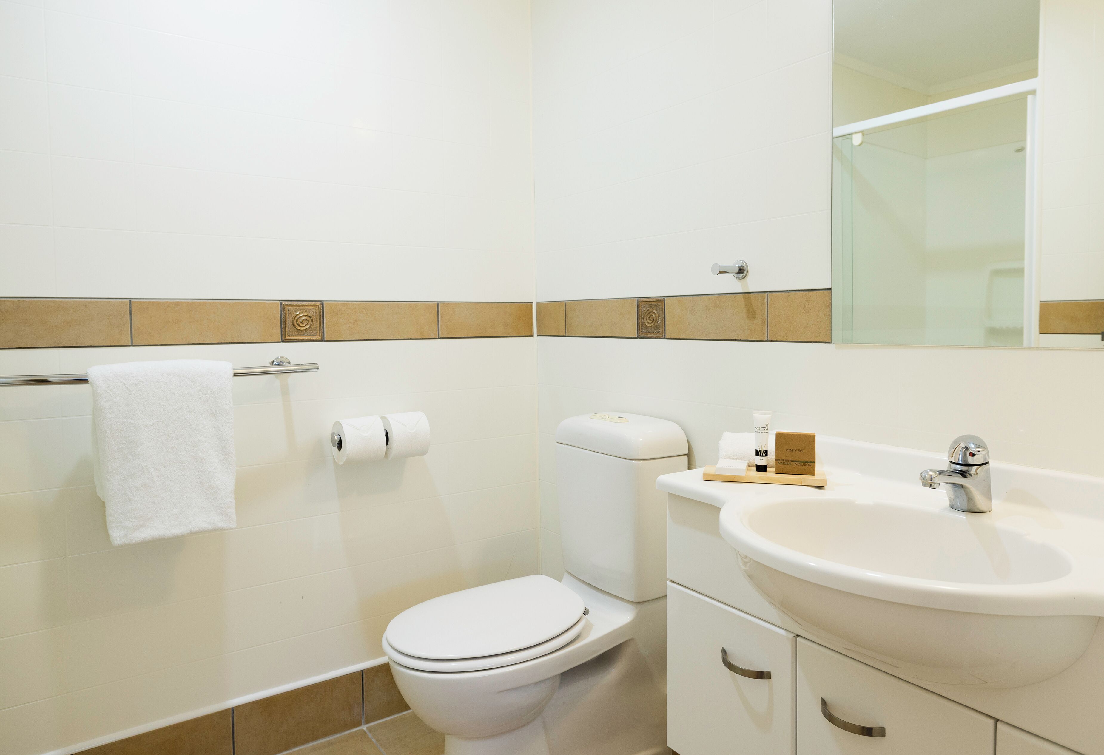 A bathroom with a toilet, sink, and mirror.