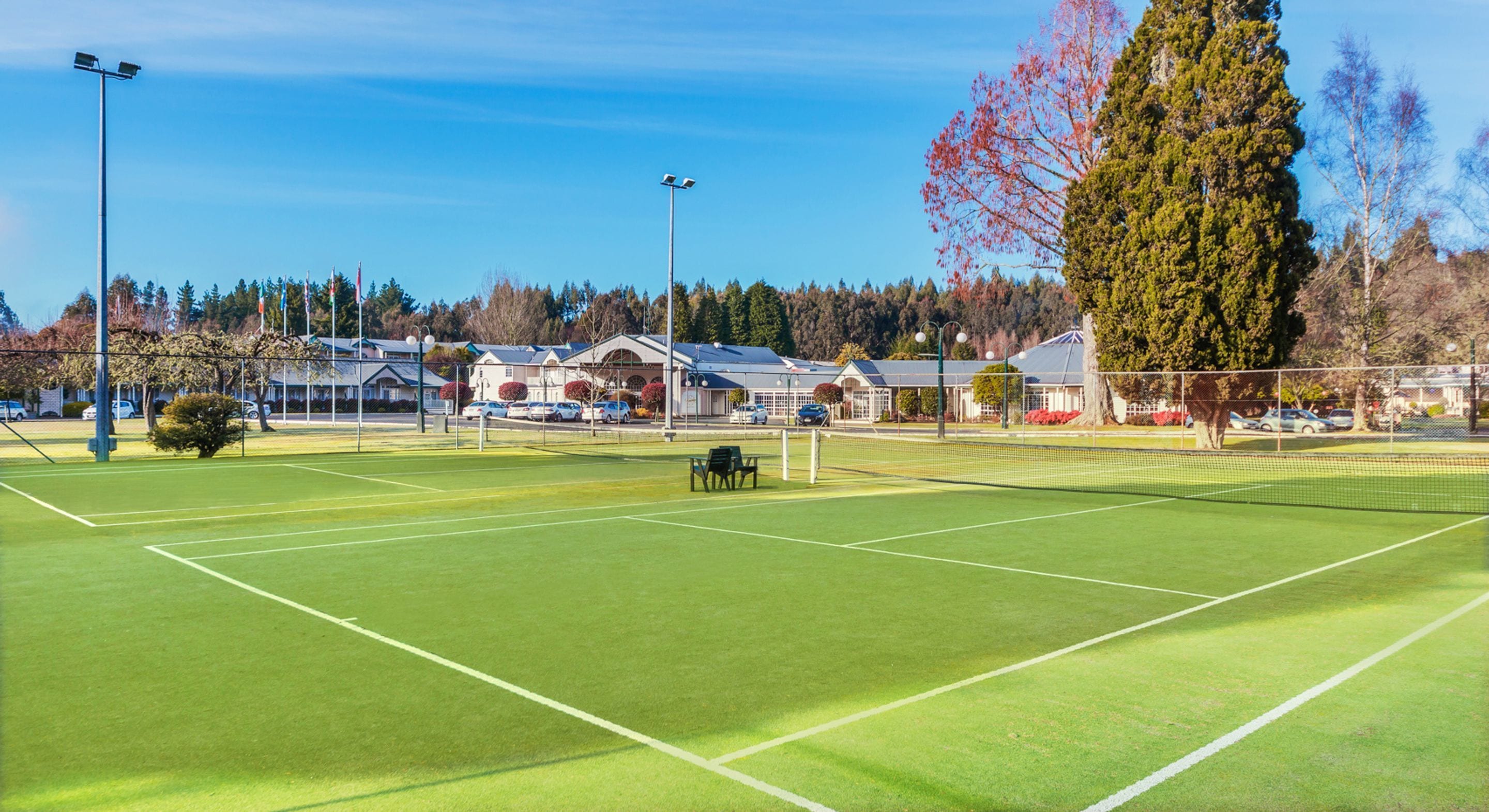Ein Tennisplatz mit Netz, umgeben von Bäumen und Gebäuden.
