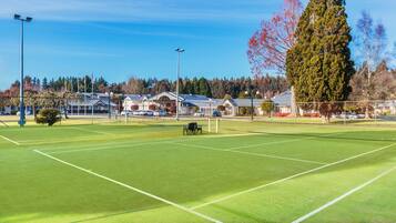 A tennis court with a net, surrounded by trees and buildings.