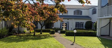 A well-maintained lawn with a paved pathway leading to a white building with large windows and a garage.