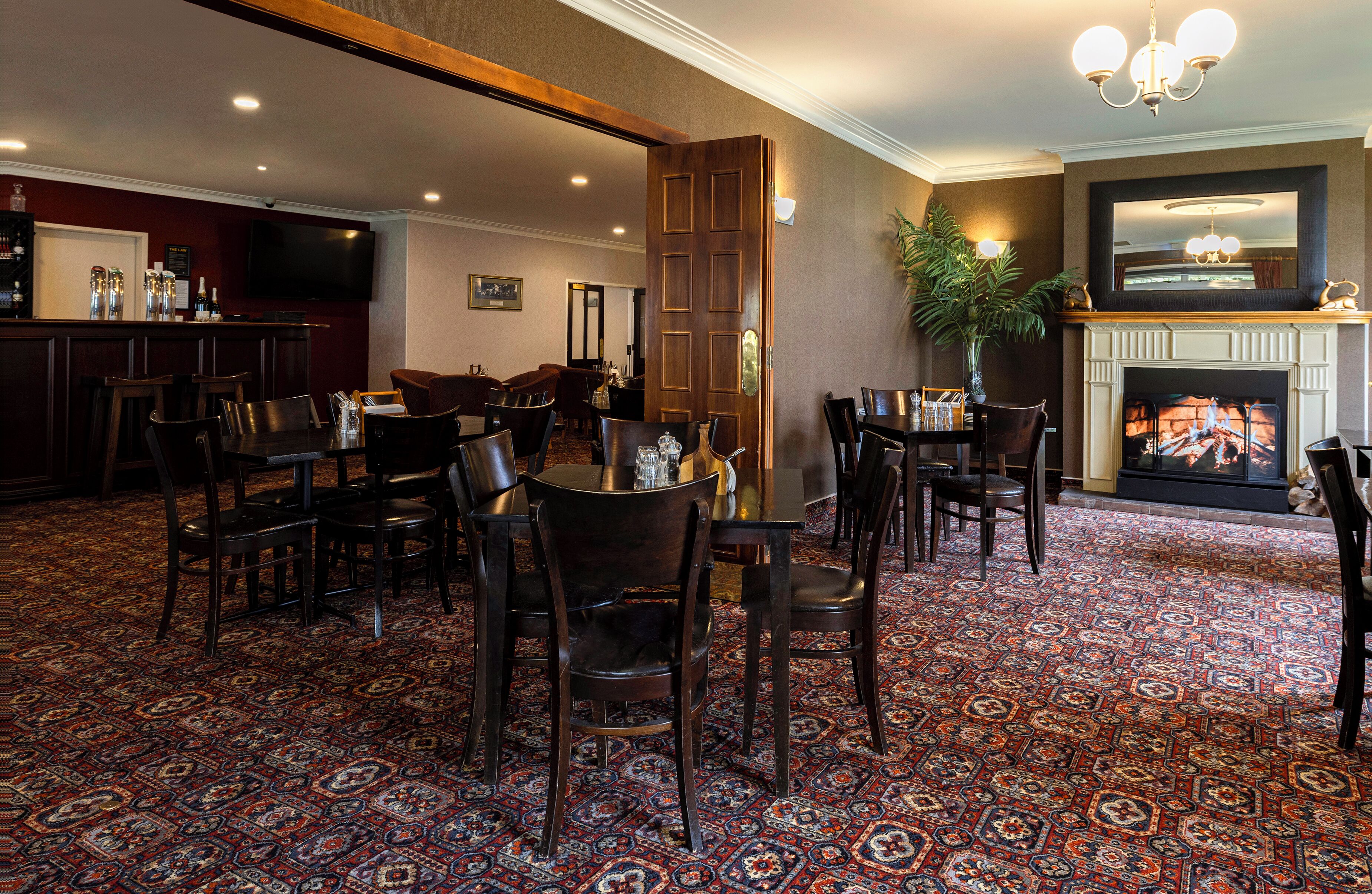 Un vestíbulo de hotel con bar, comedor y chimenea.