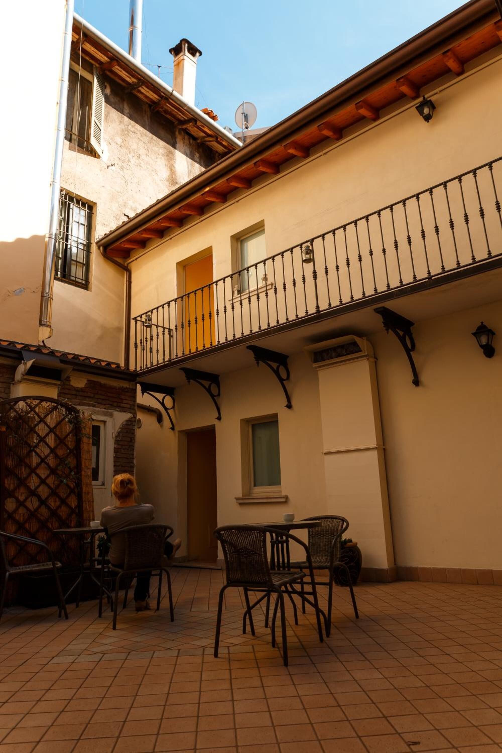 A courtyard with a tiled floor, a balcony with a wrought iron railing, and outdoor furniture.