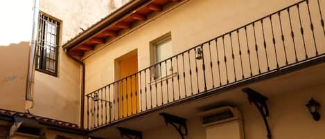 A courtyard with a tiled floor, a balcony with a wrought iron railing, and outdoor furniture.
