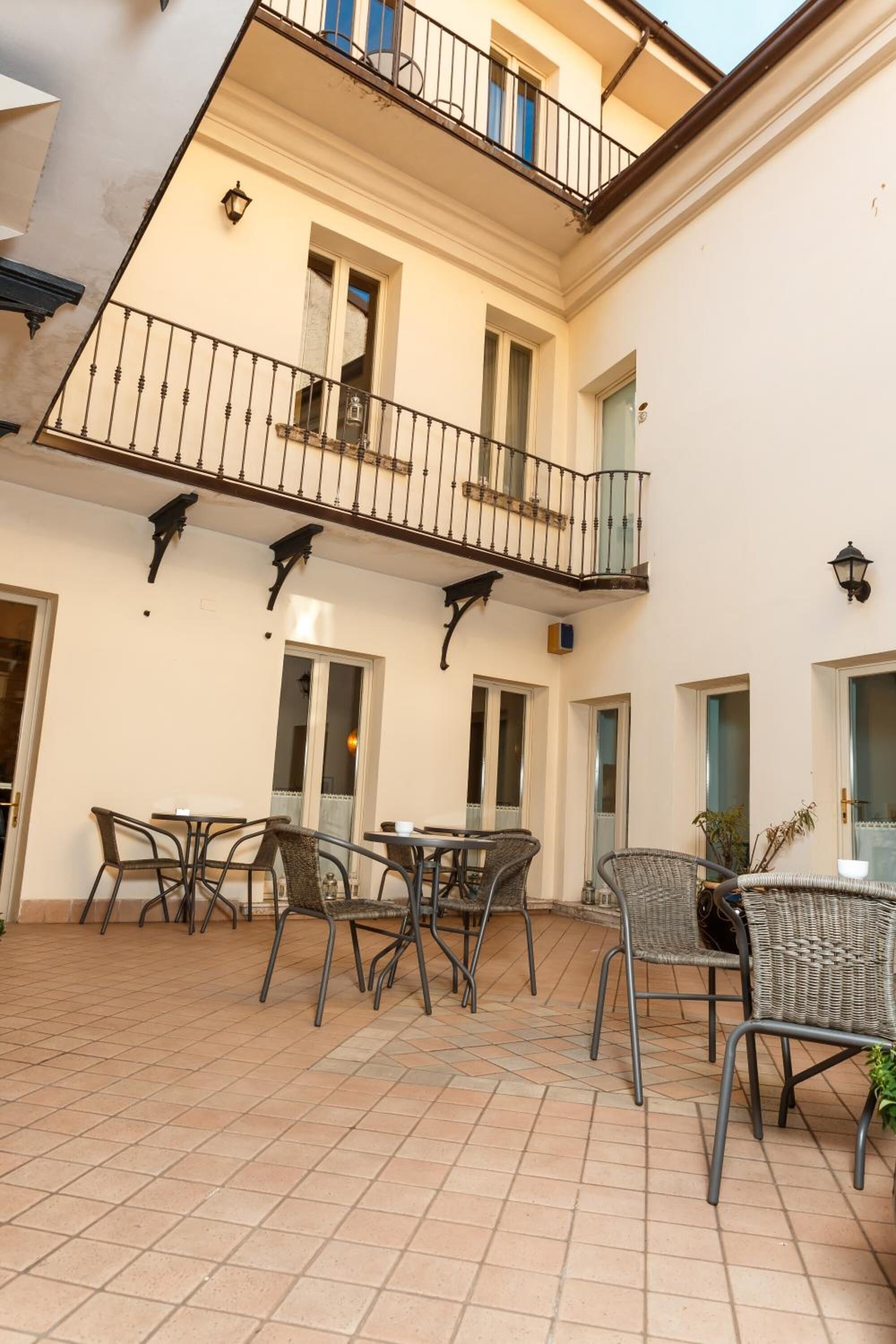 A courtyard with outdoor seating, a balcony, and a tiled floor.