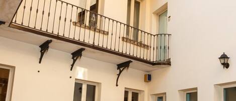 A courtyard with outdoor seating, a balcony, and a tiled floor.