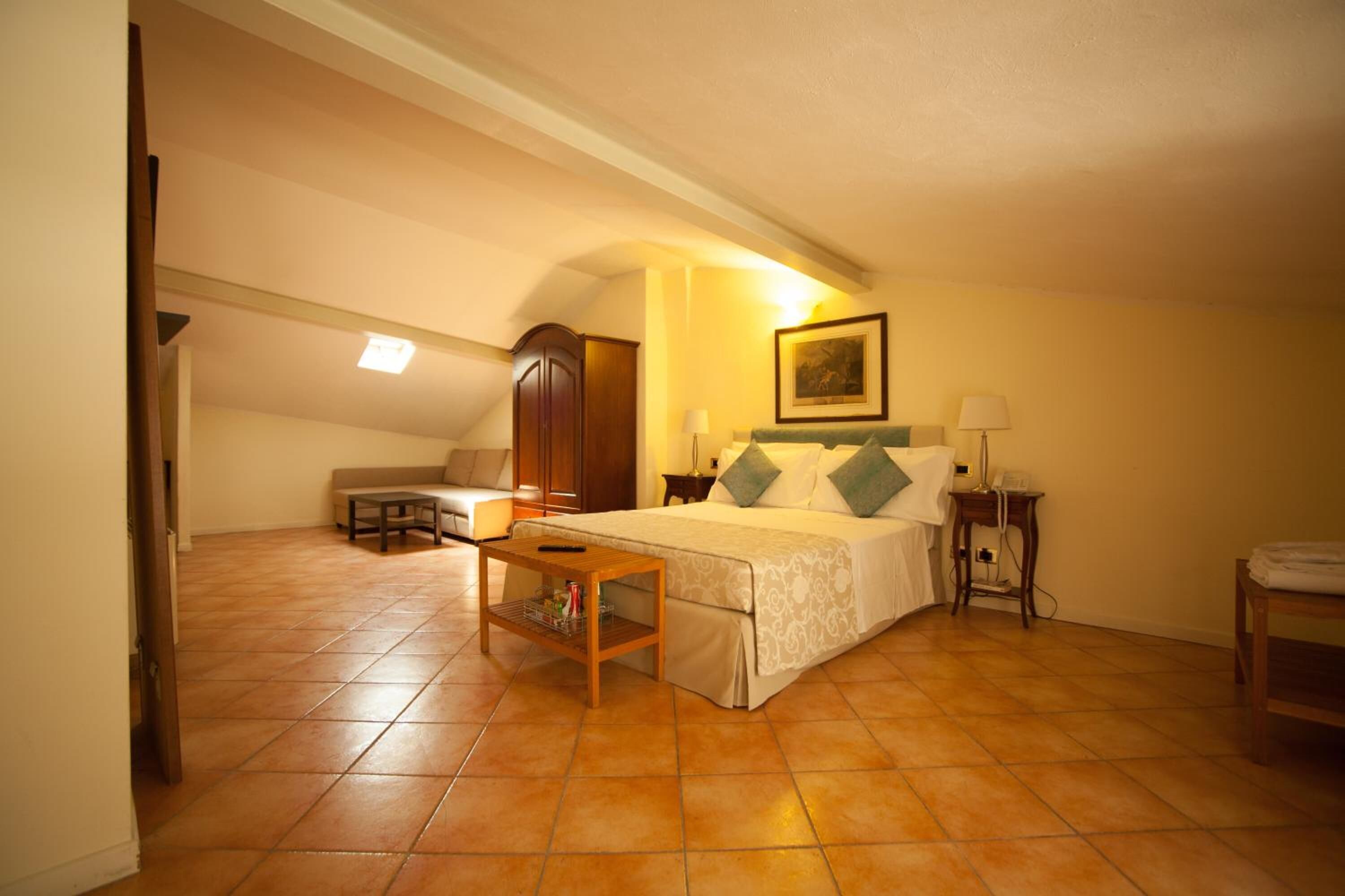 Un dormitorio con cama, mesitas de noche, una silla, un armario y un cuadro en la pared.