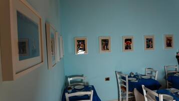 Ein Essbereich mit blauen Tischdecken, weißen Stühlen und gerahmten Bildern an der Wand.