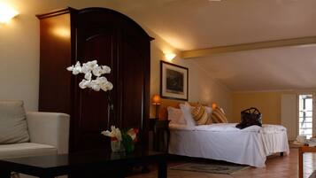 Un dormitorio con cama, mesita de noche, cómoda y un jarrón de flores blancas.