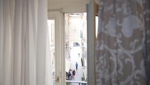 An open doorway leading to a narrow street with buildings on either side. - Albergo Orologio (Brescia)