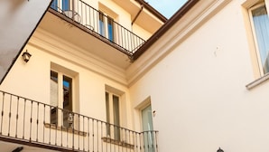 A courtyard with outdoor seating, a balcony, and a building facade. - Albergo Orologio (Brescia)