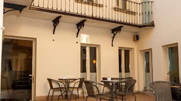 Un patio con zona de comedor, mobiliario exterior y una escalera que lleva a un piso superior.