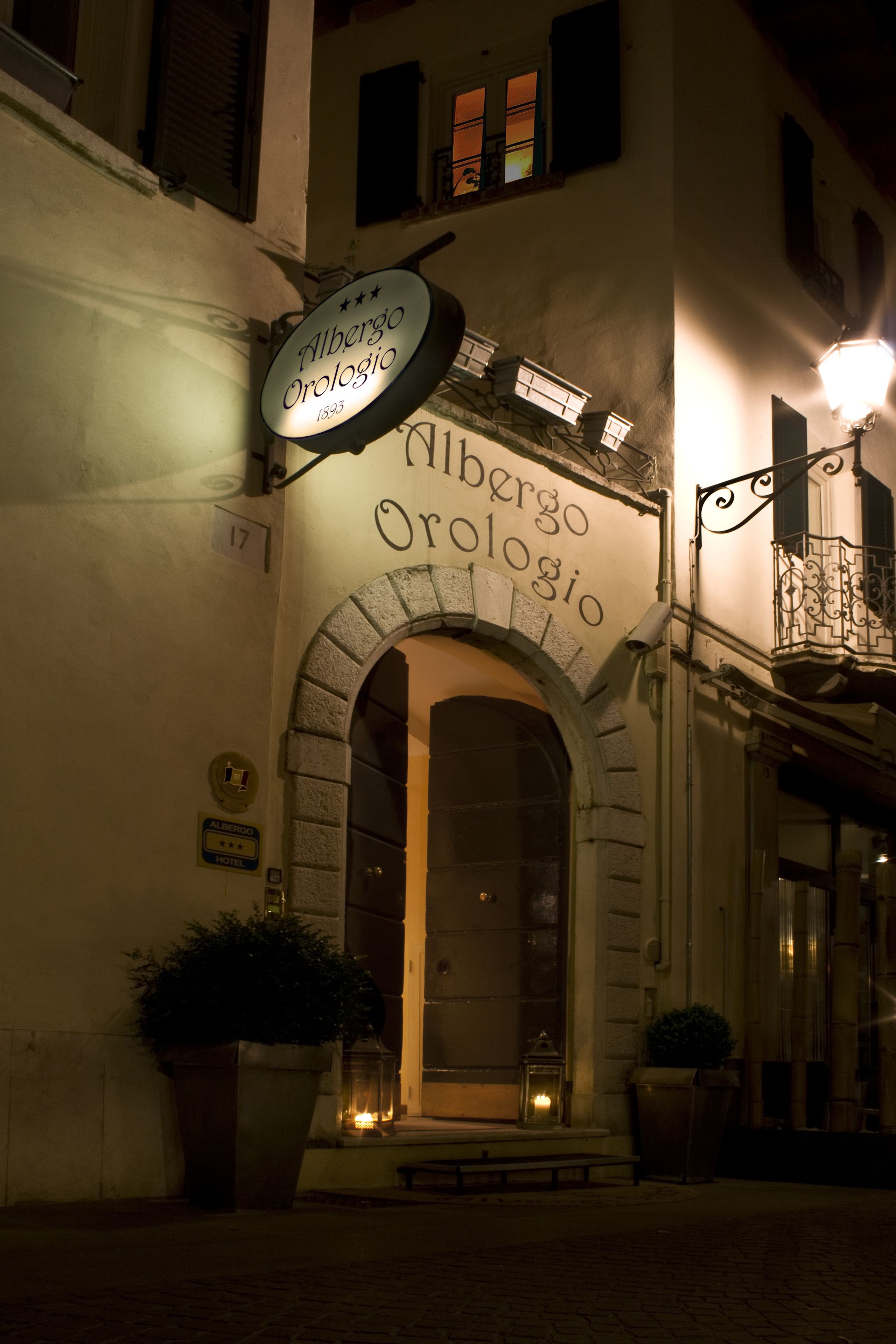 The exterior of Albergo Orologia, featuring an arched entrance, a signboard, and a potted plant.