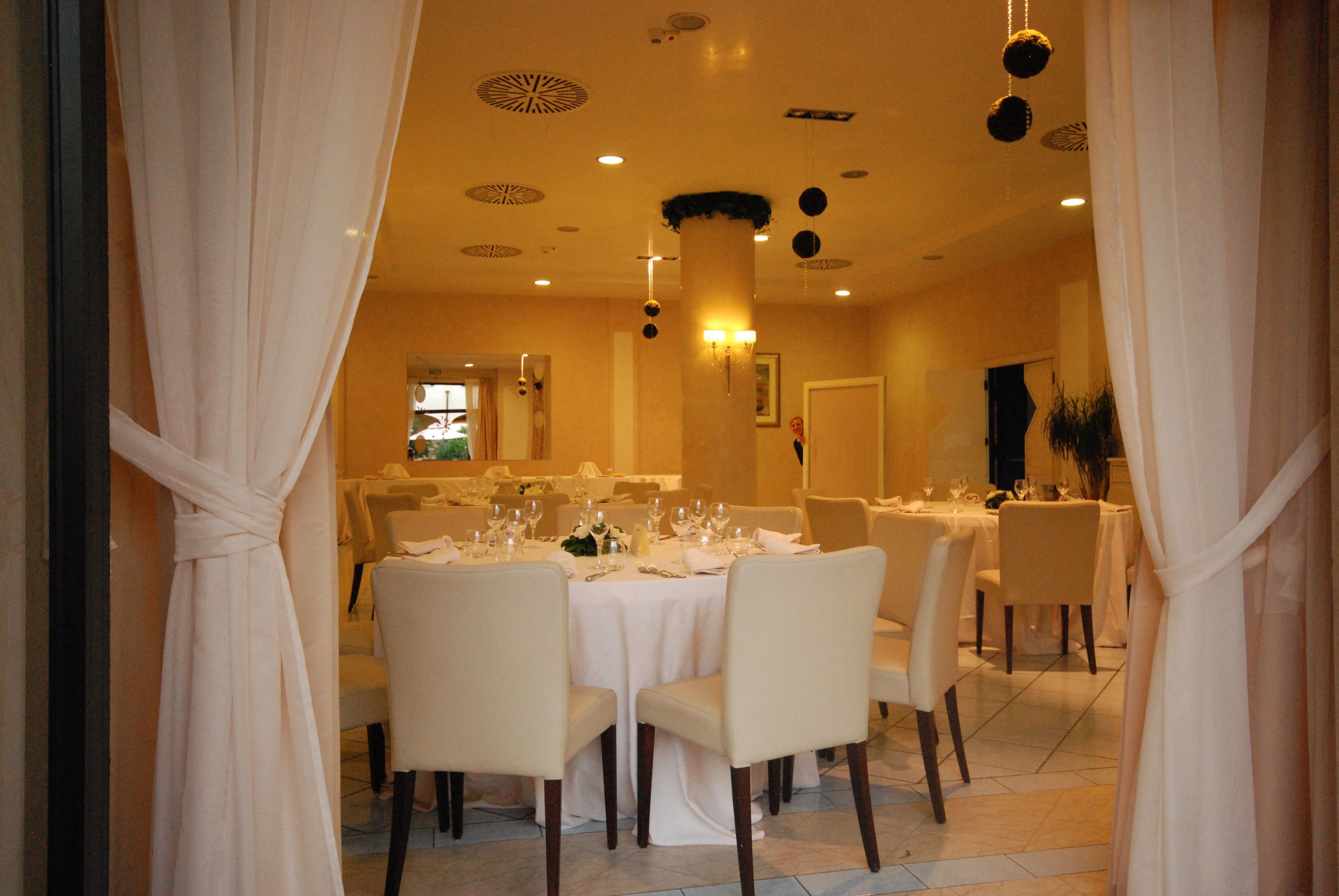 A dining area with round tables, white tablecloths, and chairs.