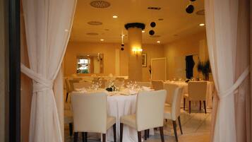 A dining area with round tables, white tablecloths, and chairs.