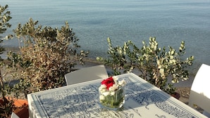 A table with a blue and white patterned tablecloth, a vase with flowers, and a view of the sea. - Mahara Hotel & Wellness (Mazara del Vallo)
