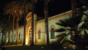 A building with arched windows and a central entrance, surrounded by palm trees. - Mahara Hotel & Wellness (Mazara del Vallo)
