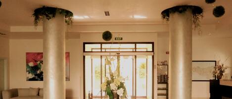 Un vestíbulo con una mesa de recepción, un sofá, una mesita de café y una mesa de vidrio decorada con flores.