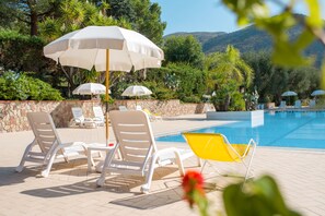 A poolside area with lounge chairs, umbrellas, and a yellow chair. - Residence Trivento (Centola)