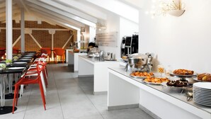 Un buffet de petit-déjeuner moderne avec une longue table, des chaises rouges et une variété de plats.