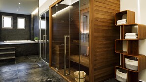 Une salle de bain moderne dotée d’une douche à parois de verre, d’un meuble-lavabo en bois et d’une étagère intégrée où sont rangées les serviettes.