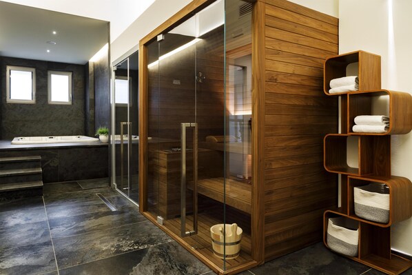 A modern bathroom with a glass-enclosed shower, a wooden vanity, and a built-in shelf with towels.