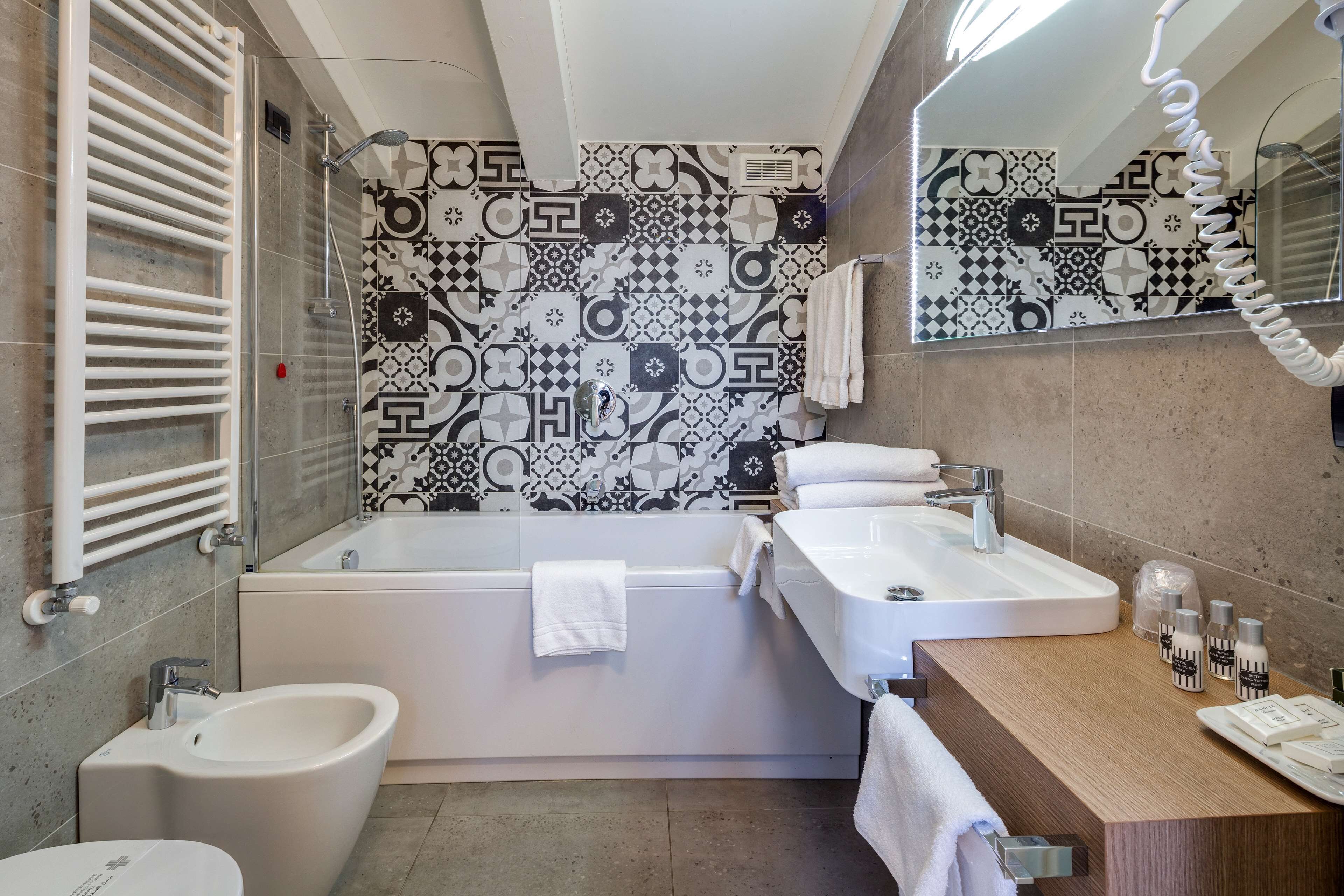 Un baño moderno con bañera, dos lavamanos, un bidé y un mueble de tocador con artículos de aseo.