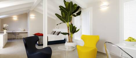 A modern living room with a large plant, a yellow chair, and a black chair.