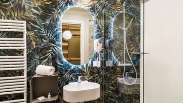 Une salle de bain avec un miroir, un lavabo et une douche.