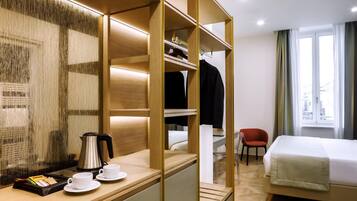 Habitación de hotel con cama, escritorio, cafetera, tazas y una silla.