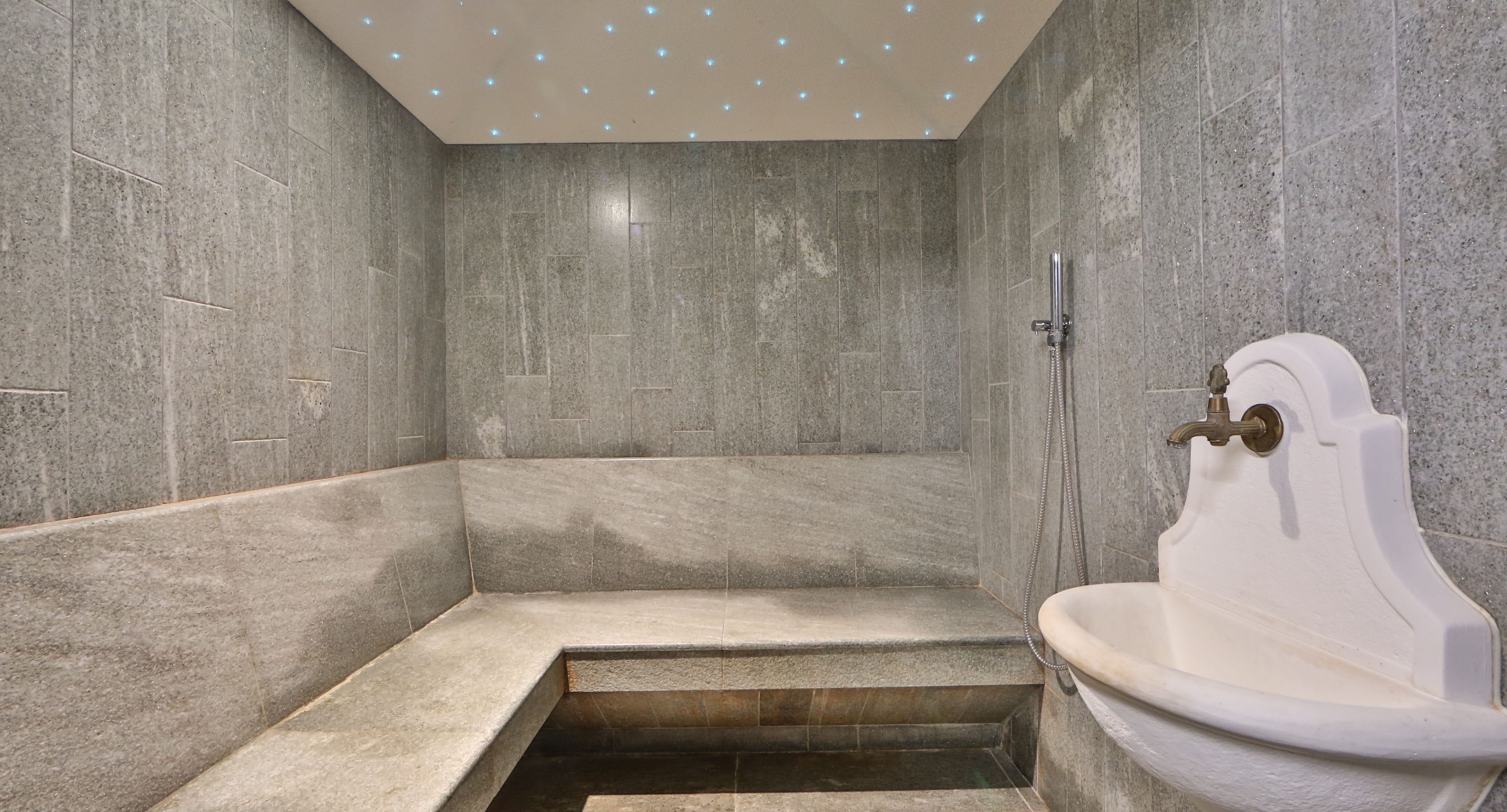 A modern bathroom with a built-in shower, a white bathtub, and a small step leading to the shower area.