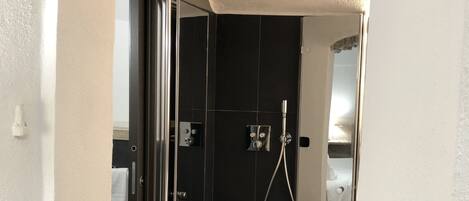 Un baño moderno con ducha, lavamanos y espejo.