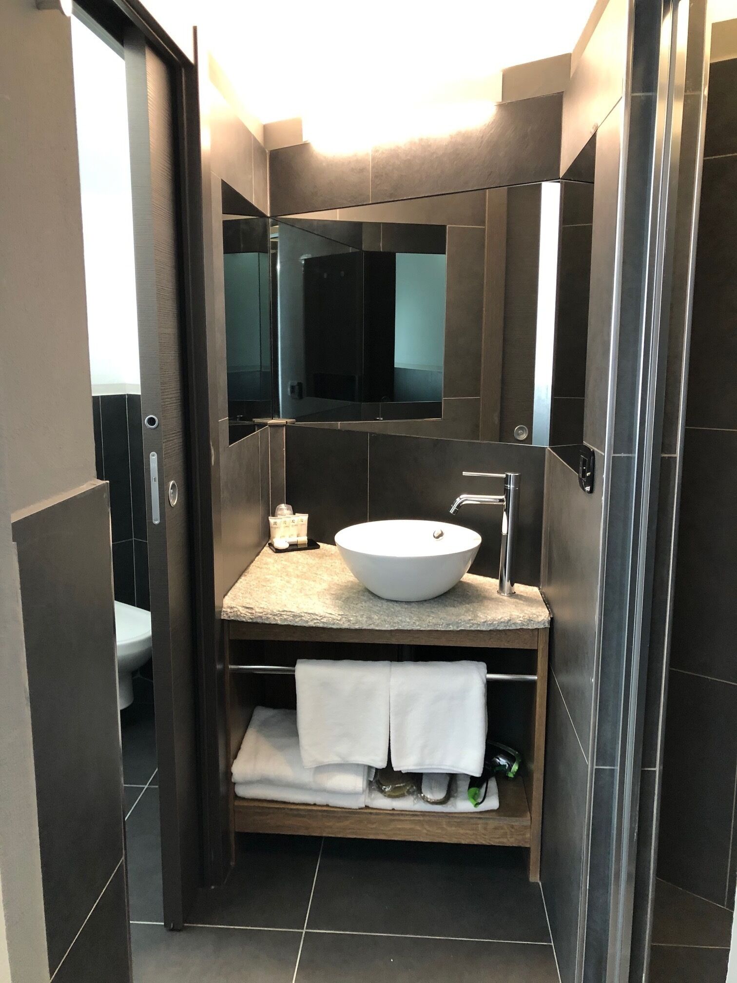 Un baño moderno con un espejo grande, un lavabo blanco y un perchero para toallas.