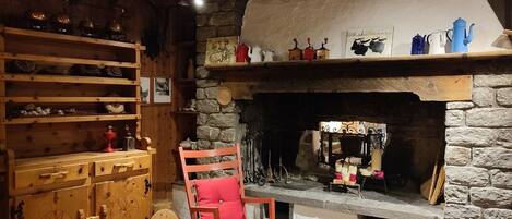 Un interior rústico con chimenea de piedra, estanterías de madera y un caballo balancín.