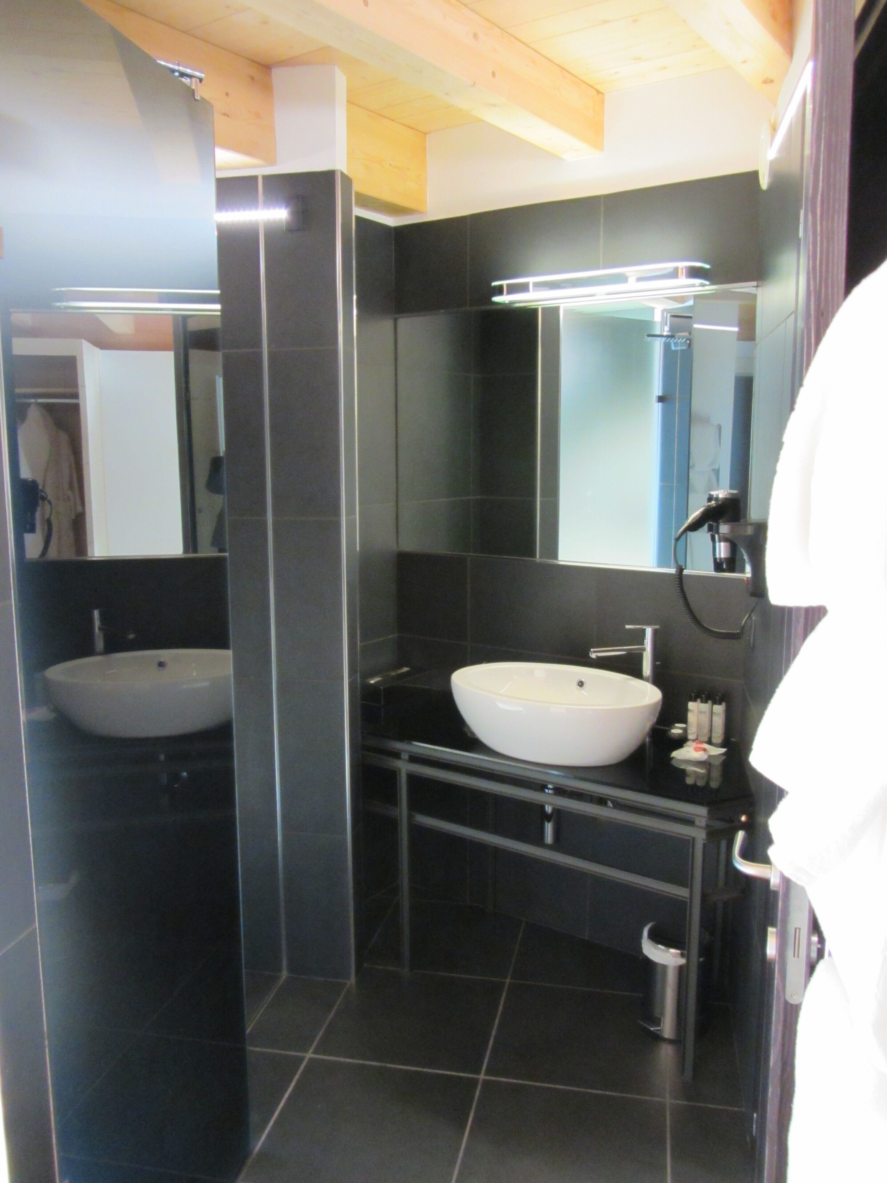 A modern bathroom with two sinks, a mirror, and a shower.
