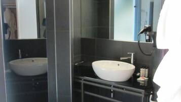 A modern bathroom with two sinks, a mirror, and a shower.