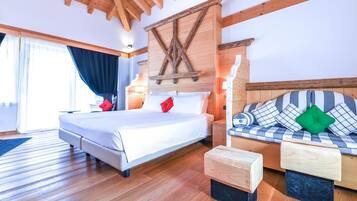 Un dormitorio con techo de madera, una cama con ropa blanca, un sofá con cojines estampados y una mesita de noche de madera.