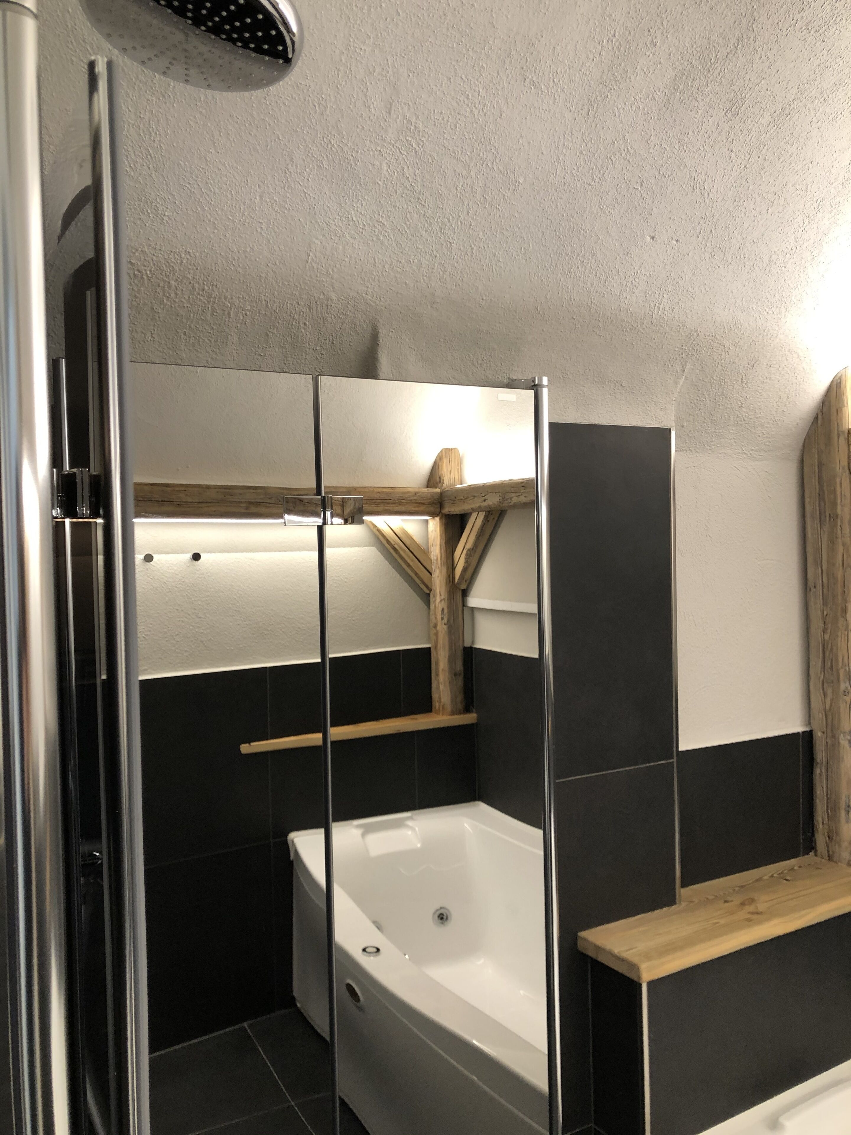 Un baño moderno con ducha de vidrio, una bañera independiente y un estante de madera.