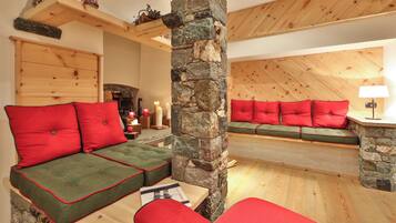 Una sala de estar acogedora con un pilar de piedra, techo de madera y chimenea de piedra.