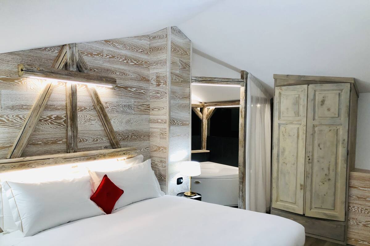 Un dormitorio con cama, armario y espejo.