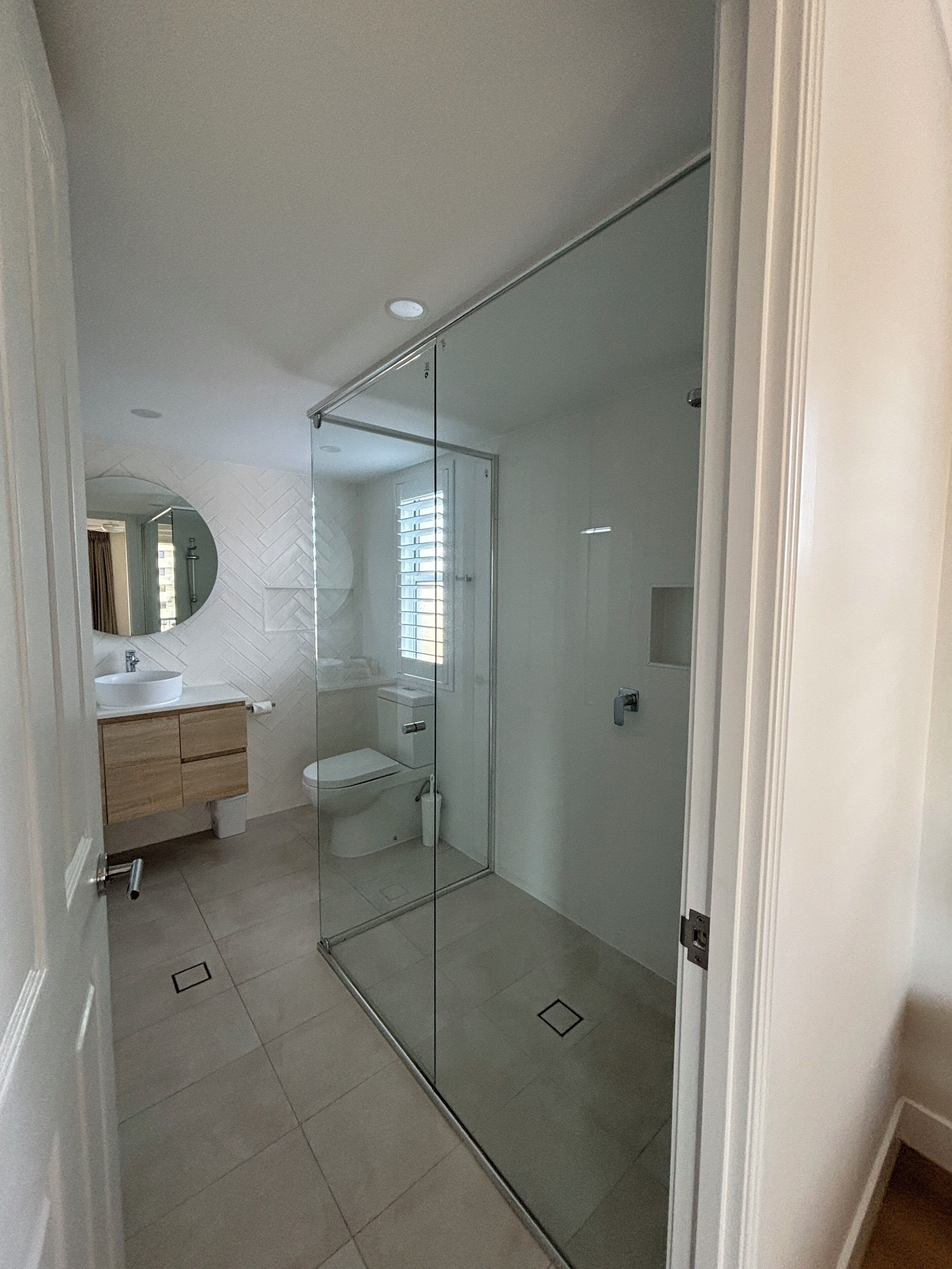 Un baño moderno con cabina de ducha de vidrio, un lavabo blanco y un inodoro.