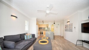 Una sala de estar moderna con un sofá gris, una mesa de centro y un ventilador de techo.