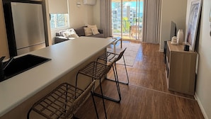 A modern kitchen with a central island, bar stools, and a built-in refrigerator. - San Mateo on Broadbeach (Broadbeach)