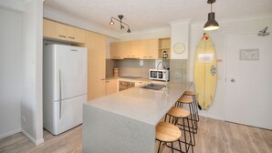 Una cocina moderna con refrigerador, microondas y una isla con taburetes de bar.